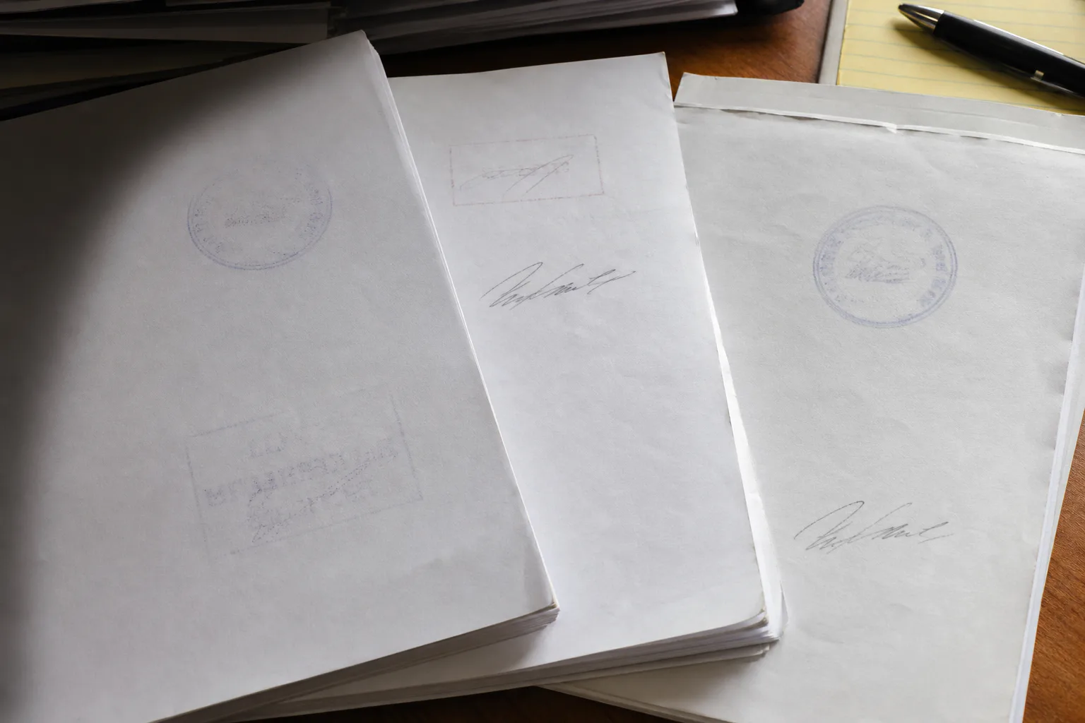 Close-up comparison of messy scanned paperwork with faint stamps, dark shadows, and uneven page edges