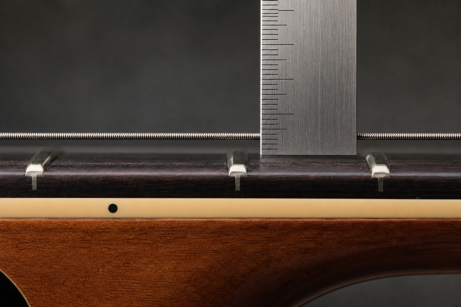 Macro view of a steel ruler measuring guitar string height at the twelfth fret